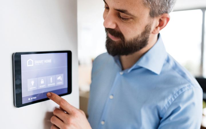 Man using smart thermostat on the way in his home